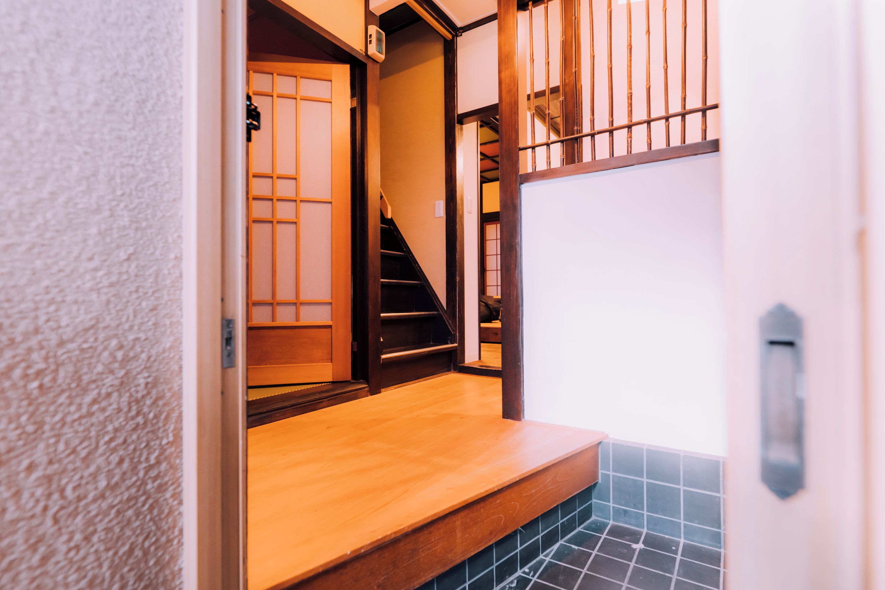 A narrow hallway with a wooden floor, a tiled wall, and a wooden door with a sliding mechanism.