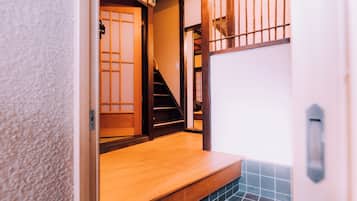 A narrow hallway with a wooden floor, a tiled wall, and a wooden door with a sliding mechanism.