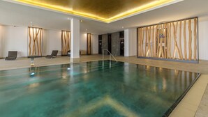 En inomhuspool med modern design, inklusive en trävägg och ett tak med infälld belysning.