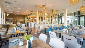 En modern restaurang med flera olika matplatser, träbord och stolar.