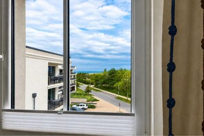 A window view of a building with balconies, a road, and greenery. - tolles Appartement mit Ostseeblick in Börgerende (Börgerende)