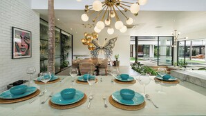Zona pranzo moderna con isola centrale, pareti in vetro e un lampadario decorativo al soffitto.