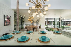 Un comedor moderno con una isla central, paredes de vidrio y un candelabro decorativo.