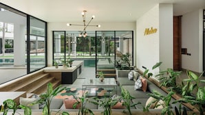 Un interno moderno con vista sulla piscina, angolo relax e un cartello con scritto 'Aloha'.