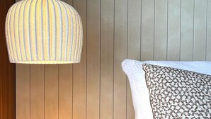 A room with a hanging light fixture and a patterned pillow on a bed. - Modern holiday home with sauna (St. Lambrecht)