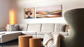 A modern living room with a sectional sofa, two wooden side tables, and artwork on the wall. - Modern holiday home with sauna (St. Lambrecht)