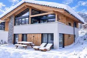 A modern two-story wooden house with large windows and a balcony, surrounded by snow. - Modern holiday home with sauna (St. Lambrecht)