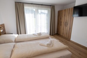 Ein Schlafzimmer mit zwei Betten, einem Holzschrank und einem Fernseher an der Wand.