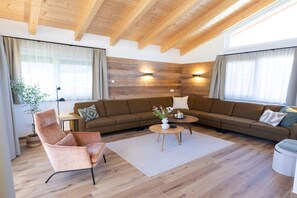 Ein modernes Wohnzimmer mit einem Ecksofa, einem runden Couchtisch und einer Holzbalkendecke.