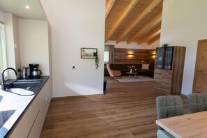 Een moderne keuken met een spoelbak, koffiezetapparaat, en een eethoek met een tafel en stoelen.