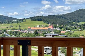 A town with a prominent building with a red roof and a tower, surrounded by green hills and trees. - Holiday home directly on the ski slope with sauna (St. Lambrecht)