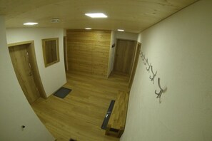 Ein Zimmer mit Holzboden, einer Bank, einer Tür und einem Wandhaken.