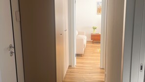 A hallway with wooden flooring, white walls, and a bed in the distance. - Bright apartment in downtown Lugano (Lugano)