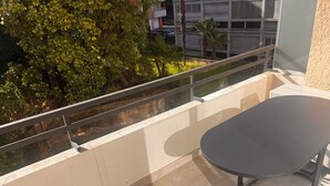 A balcony with a metal railing, a black table, and a view of trees and buildings. - Bright apartment in downtown Lugano (Lugano)