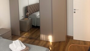 A bedroom with a bed, a bedside table, a lamp, a wardrobe, and a door. - Bright apartment in downtown Lugano (Lugano)