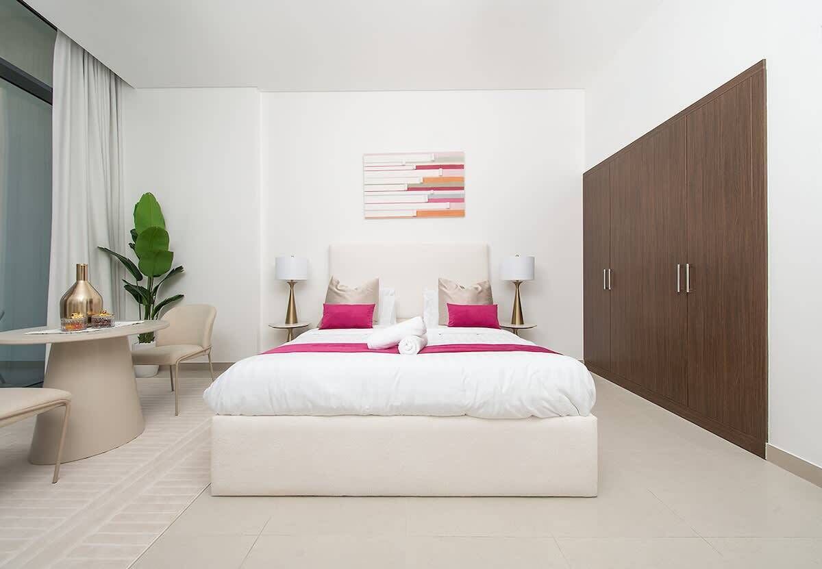 Quarto de hotel moderno com uma cama grande, luminárias de cabeceira, uma escrivaninha e um guarda-roupa.