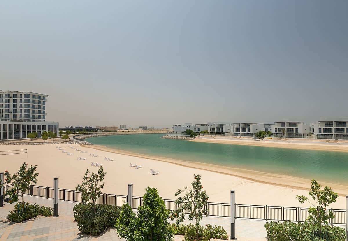 A beachfront hotel with modern architecture, a sandy beach, and a clear view of the sea.