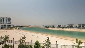 A beachfront hotel with modern architecture, a sandy beach, and a clear view of the sea.