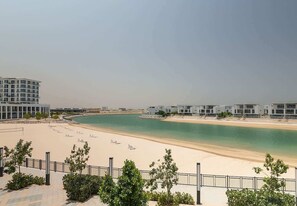 A beachfront hotel with modern architecture, a sandy beach, and a clear view of the sea.