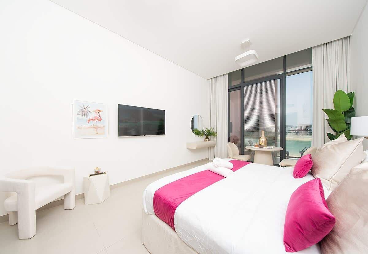 Une chambre d’hôtel moderne dotée d’un grand lit, d’un coin salon, d’une petite table et d’une grande fenêtre offrant une vue agréable.