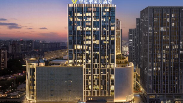 A modern hotel with a prominent vertical design, multiple floors, and illuminated signage. - Vienna Hotel Fuzhou Cangshan Wanda (Fuzhou)