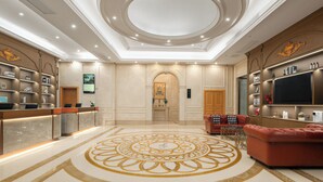 A hotel lobby with a reception desk, seating area, and a large decorative floor pattern. - Vienna Hotel Fuzhou Cangshan Wanda (Fuzhou)