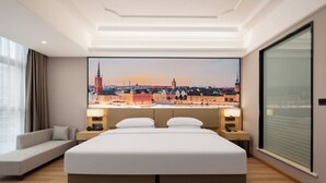 A hotel room with a large bed, a sofa, a cityscape view, and a large window. - Vienna Hotel Fuzhou Cangshan Wanda (Fuzhou)
