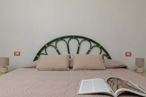 A bed with a green metal headboard, two beige pillows, and a magazine on the bed. - Casa dell'Edera F2/1 by Wonderful Italy (San Teodoro)