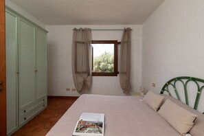 A bedroom with a bed, a window with curtains, a wardrobe, and a green headboard. - Casa dell'Edera F2/1 by Wonderful Italy (San Teodoro)