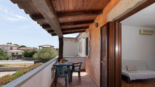 Een balkon met een tafel en stoelen, een bank en uitzicht op de omgeving.