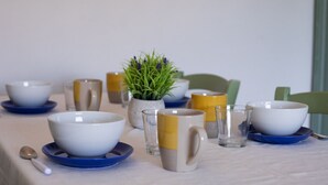 Een eettafel met kommen, glazen en een bloempot.