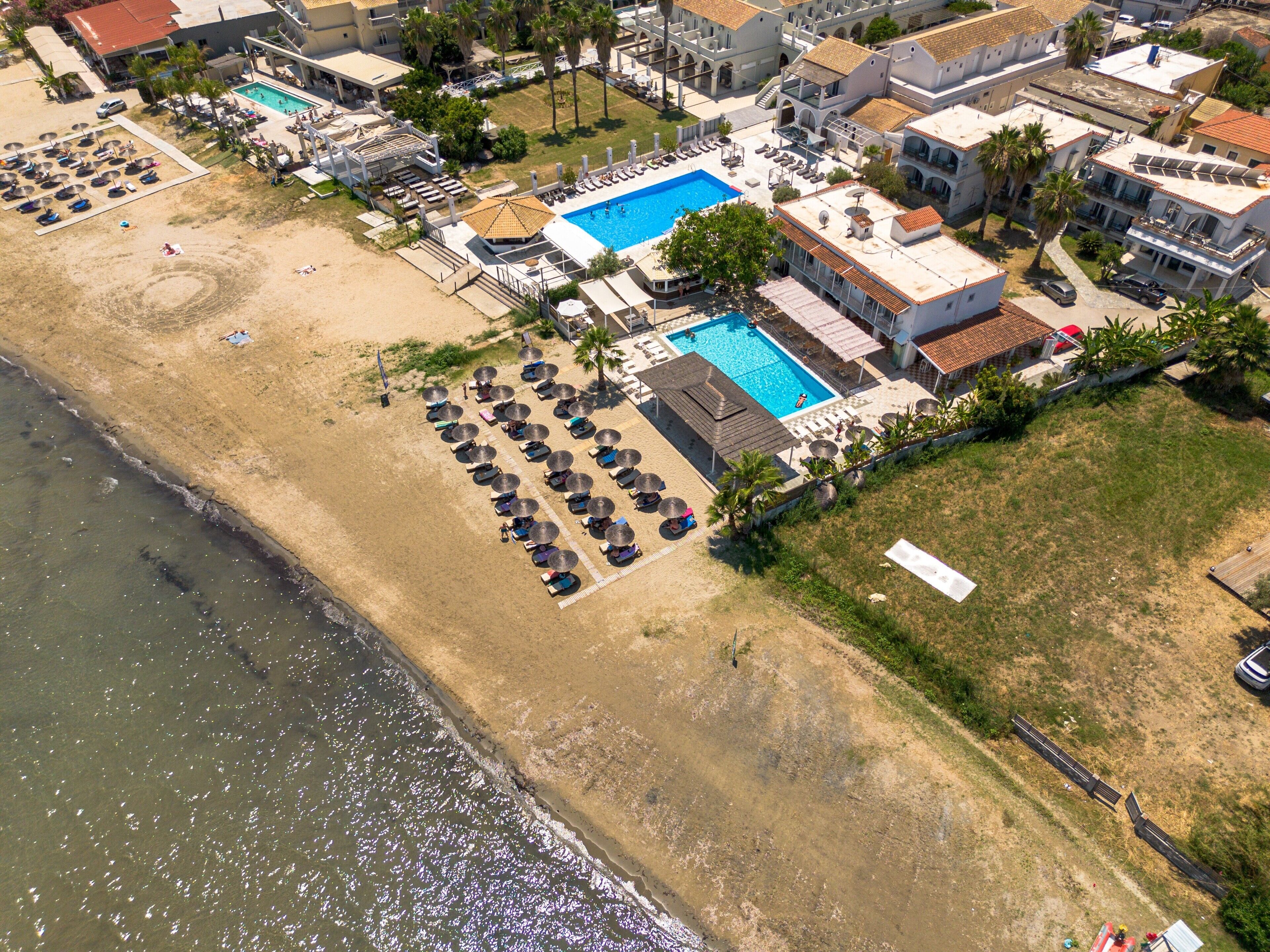 Vue aérienne d’un hôtel situé sur la côte, avec une piscine, des chaises longues sur la plage et une plage.