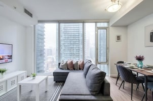 A modern living room with a sofa, a dining table, and a TV.
