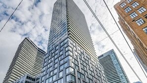 Un edificio de gran altura con un diseño arquitectónico moderno, que presenta una cuadrícula de ventanas y una entrada destacada en esquina.