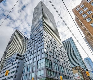 A high-rise building with a modern architectural design, featuring a grid of windows and a prominent corner entrance. - Peter Street Downtown Toronto Suites (Toronto)