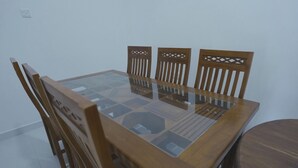 A dining table with a glass top and wooden chairs. - Green Peak View Haputale (UP)