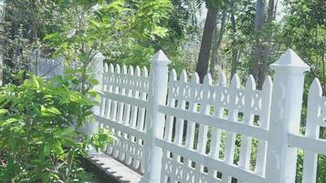 A white picket fence with a decorative top, surrounded by lush green foliage.
