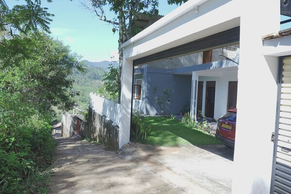Una casa moderna con entrada pavimentada, un garaje y un jardín pequeño.