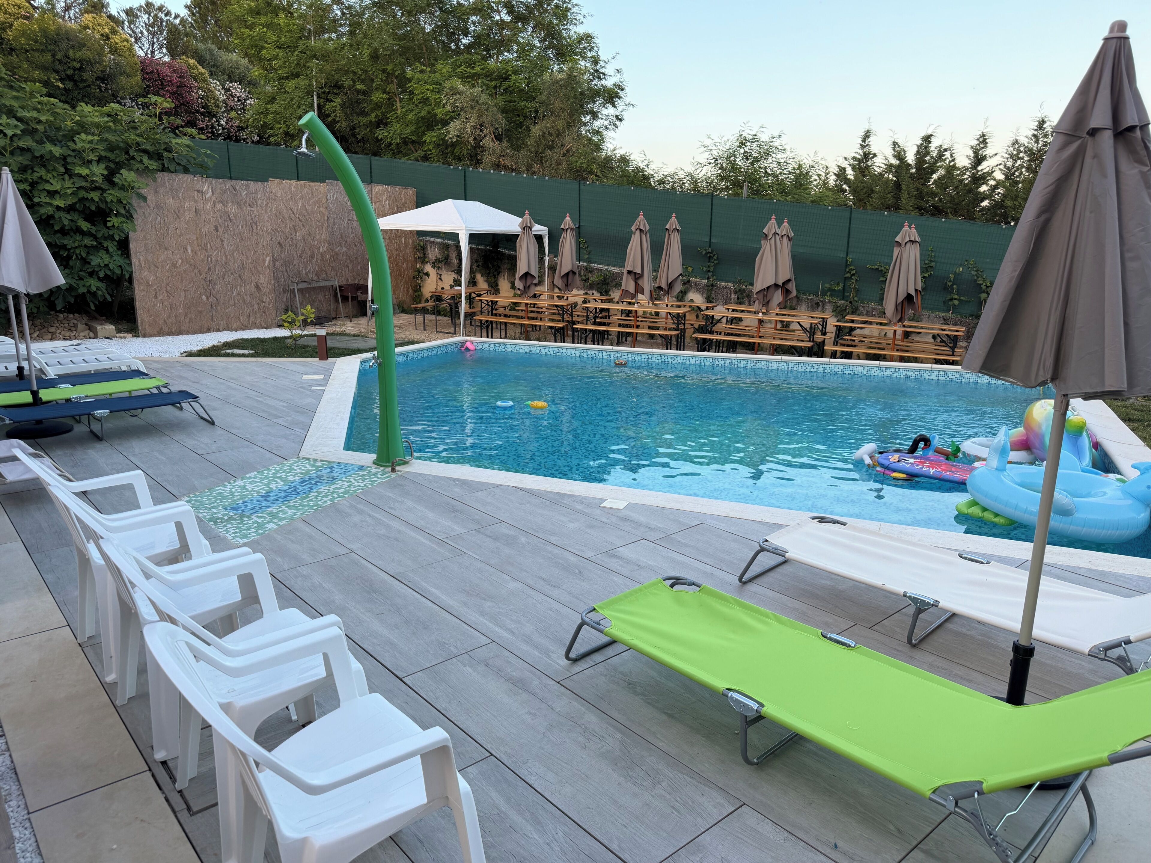 A swimming pool with lounge chairs, a water feature, and a covered seating area.