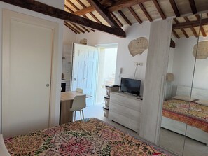 Een slaapkamer met een bed, een televisie, een bureau met stoel, en een kledingkast.