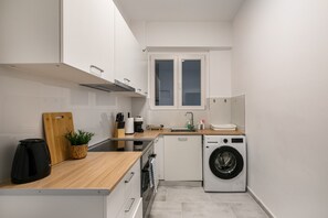 Eine kleine Küche mit Waschmaschine, Holz Arbeitsplatte und Fenster.