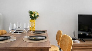 A dining table with black plates, clear wine glasses, and a yellow vase with flowers. - Sylka - Warm 1-BR & Balcony in Athens (Athens)