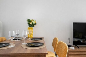 A dining table with black plates, clear wine glasses, and a yellow vase with flowers. - Sylka - Warm 1-BR & Balcony in Athens (Athens)