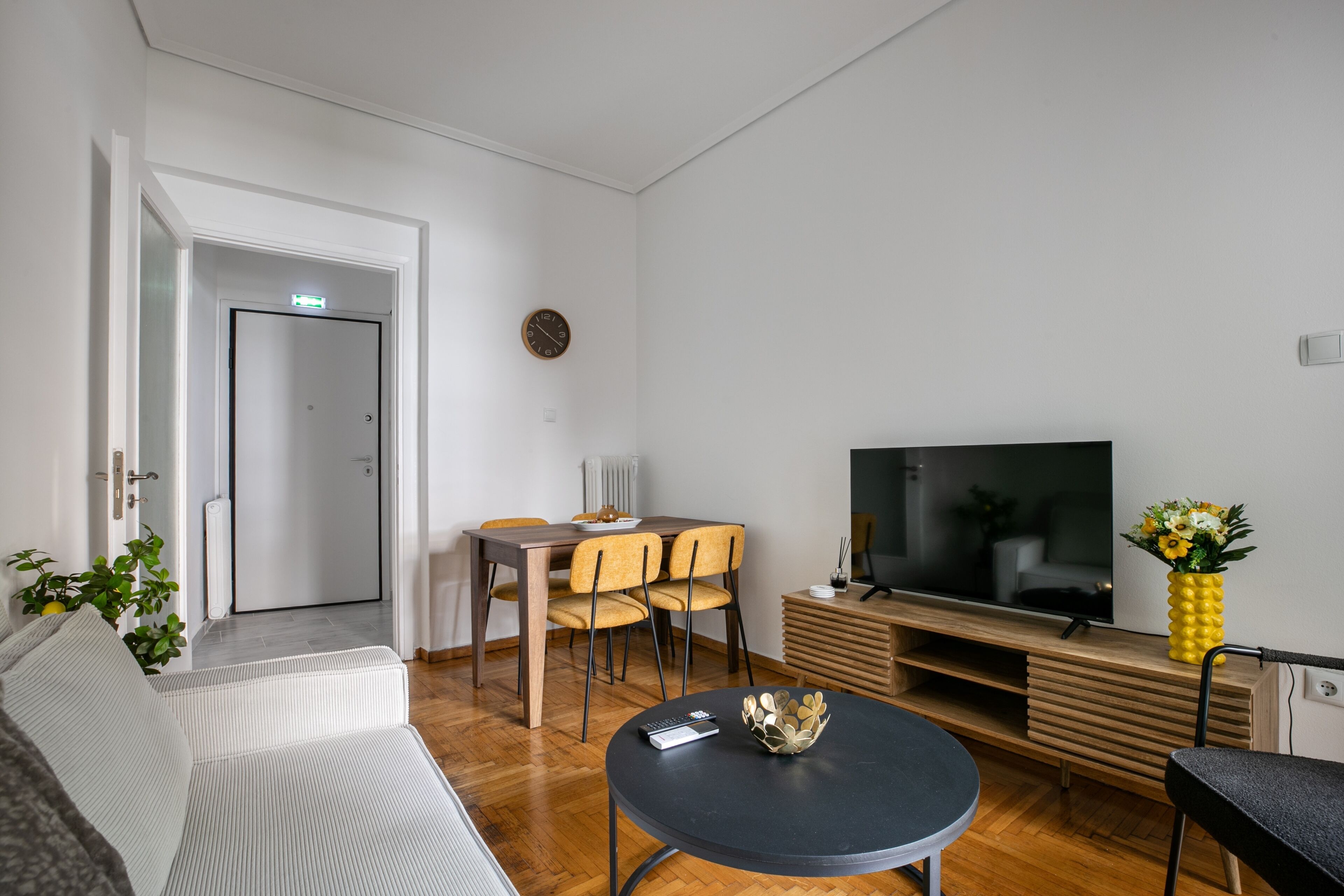 A modern living room with a sofa, dining table, chairs, a TV, and a coffee table.
