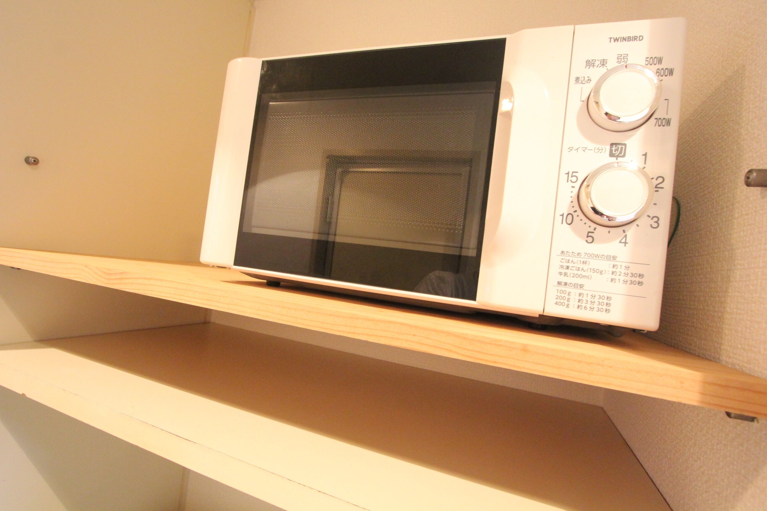 A microwave oven on a wooden shelf.