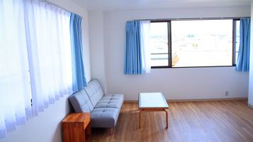 A room with a sofa, a small table, and a window with curtains.