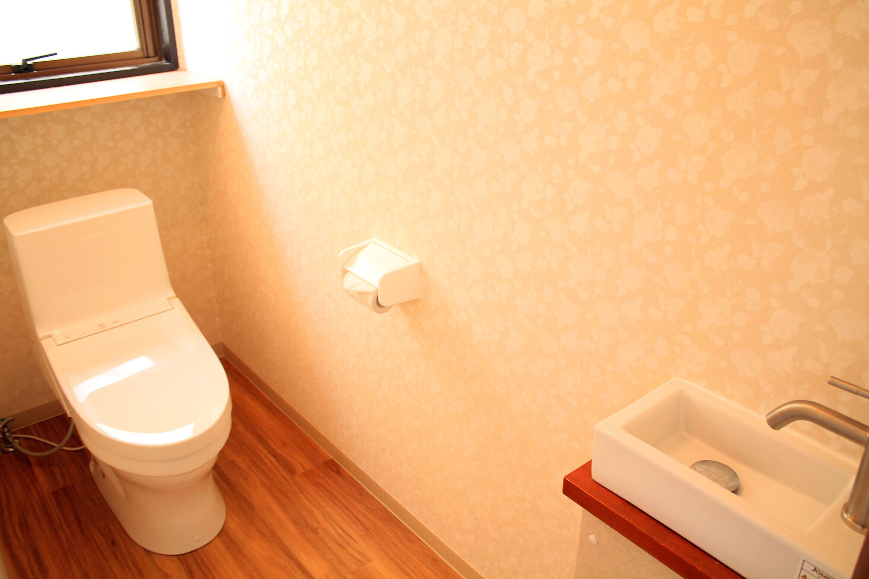 Un baño con inodoro, lavamanos y dispensador de toallas de papel.