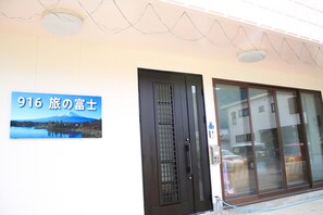 Ein Hotel mit Eingangsbereich, einer großen Glasdoor, einem Schild mit japanischen Schriftzeichen und Blick auf einen Berg.