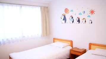 Una habitación con dos camas individuales, una ventana con cortinas y un adhesivo mural con pingüinos y elementos meteorológicos.