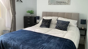 Una camera da letto con un letto, una cassettiera, uno specchio e una pianta.